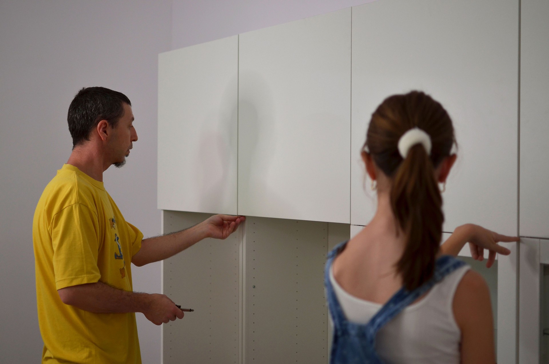 A father and a daughter are working together to install cabinets.